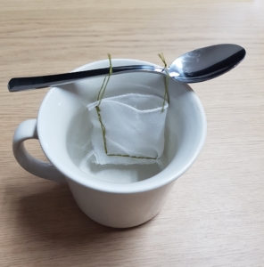 Teebeutel hängt an einem Löffel in einer Tasse