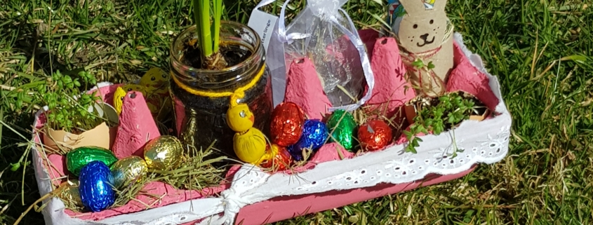 Foto eines Osternests für den Garten to go mit einer Blume im Glas, Samen-Bomben in einem weißen Säckchen, Kresse in einer Eierschale und Süßigkeiten (Foto: Katharina Gebel)