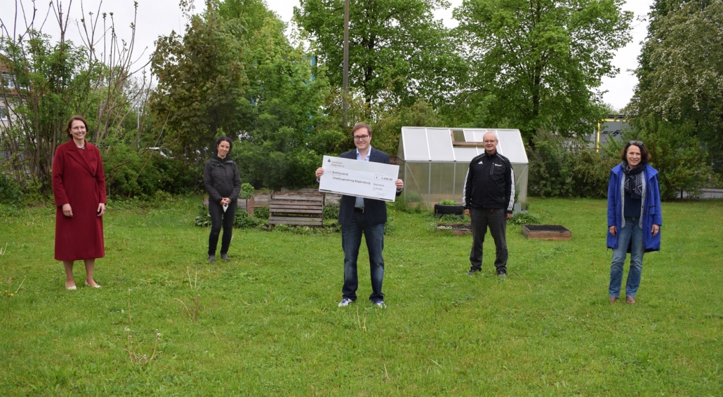 Foto der Spenden·übergabe. Von links nach rechts auf dem Bild sind: Irene Dullinger, Vorstands·vorsitzende der Sparkasse Regensburg, Katharina Gebel, Projekt·leitung des Inklusiven Gartens, Philipp Seitz, Vorsitzender des Stadtjugendring Regensburg mit dem Scheck, Detlef Staude, stell·vertretender Vorsitzender des Stadtjugendring Regensburg, und Gertrud Maltz-Schwarzfischer, Ober·bürger·meisterin von Regensburg. Foto·grafiert hat Carolin Winkelmeier von der Sparkasse Regensburg.