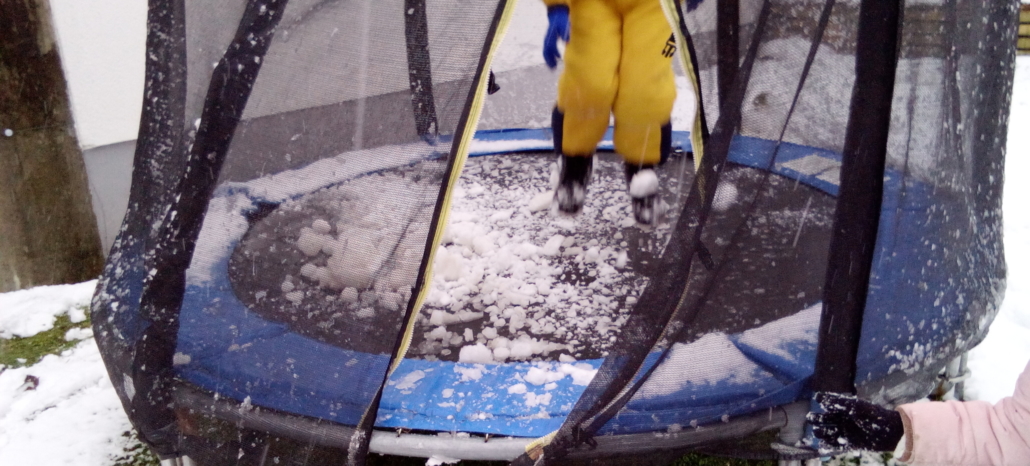 Kind springt im Trampolin, das voller Schnee ist (Foto: Katharina Gebel)