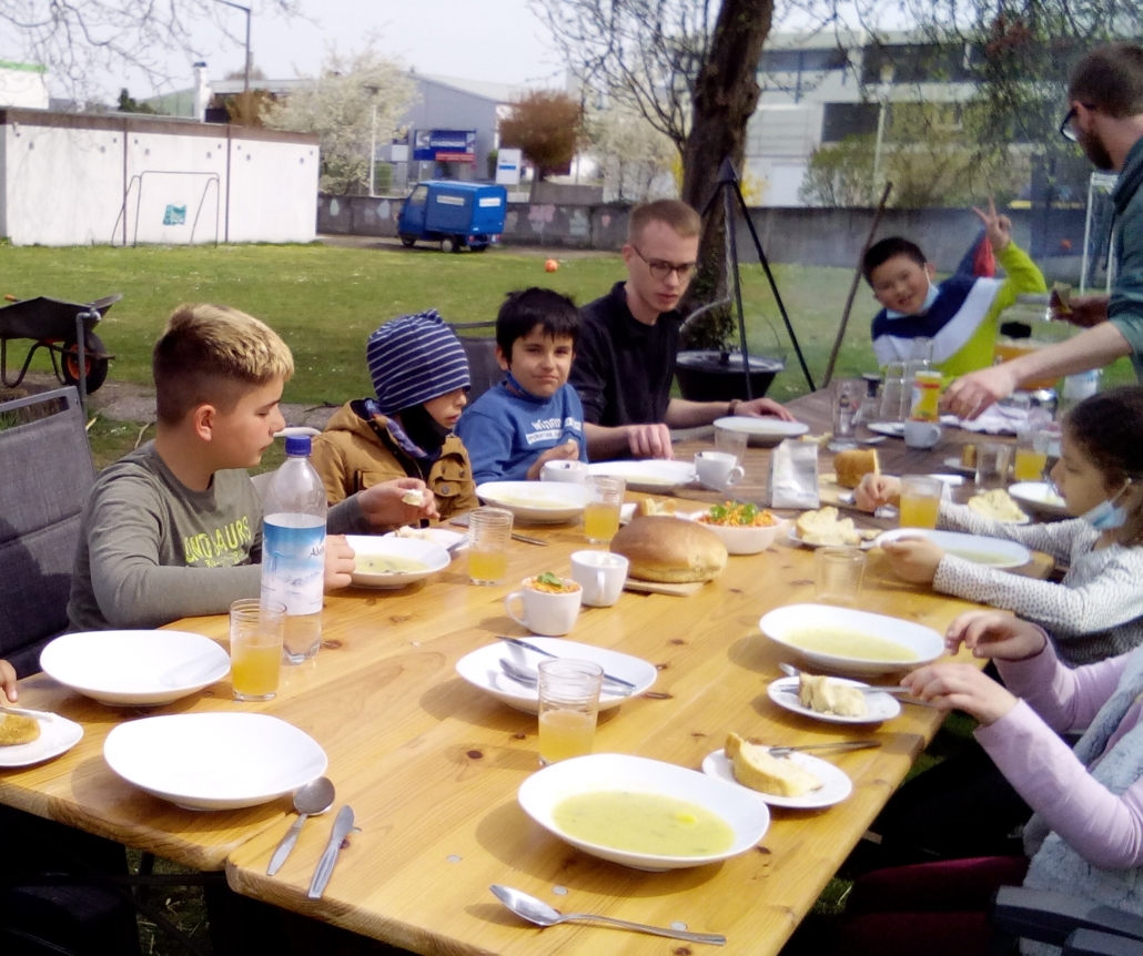 Kinder und Betreuer:innen sitzen zusammen am Tisch und essen das Oster-Menü (Foto: Katharina Gebel)