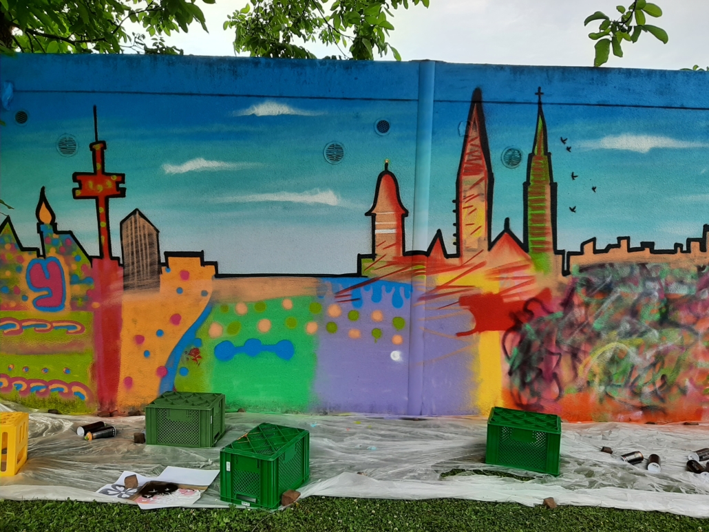 Das Foto ein Grafiti auf der Rückwand unserer Garagen. Das Grafiti ist die ganz bunt gesprühte Skyline von Regensburg. (Foto: Barbara Kießling/FreiwilligenAgentur Regensburg)