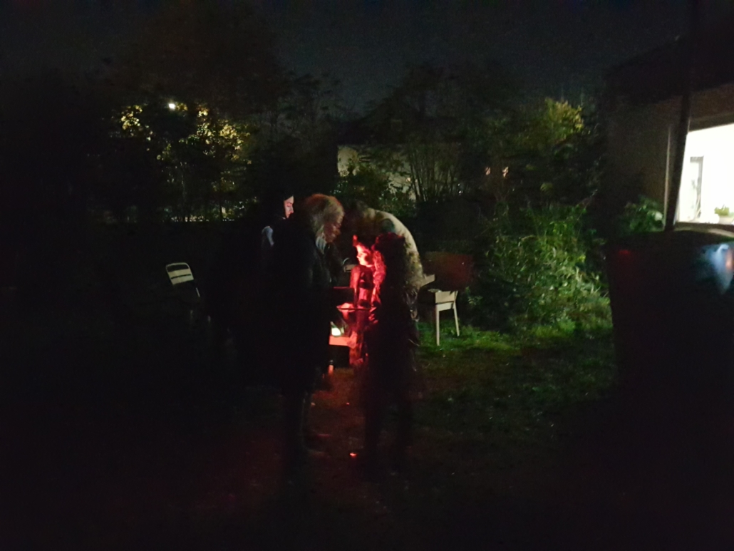 Foto von Menschen im dunklen Garten. Dazwischen ist rotes Licht. (Foto: Katharina Gebel)