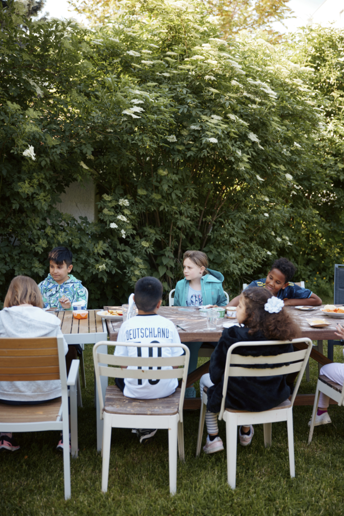 Das Foto zeigt mehrere Kinder an einem Tisch im Garten. Sie frühstücken. (Foto: ©BJR/Johnke)