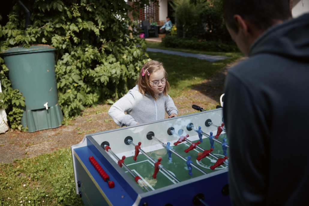 Das Foto zeigt ein Kind, das mit einem Mitarbeiter Tischkicker spielt. (Foto: ©BJR/Johnke)
