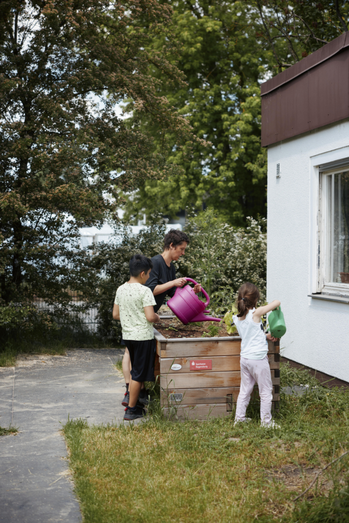 Das Foto zeigt 2 Kinder und die Projektleitung beim Gießen. (Foto: ©BJR/Johnke)