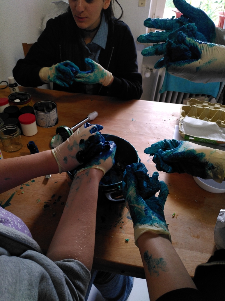 Das Foto zeigt die Hände von vier Jugendlichen, die gerade aus blauer Seifenmasse Seife kneten. (Foto: Katharina Gebel)