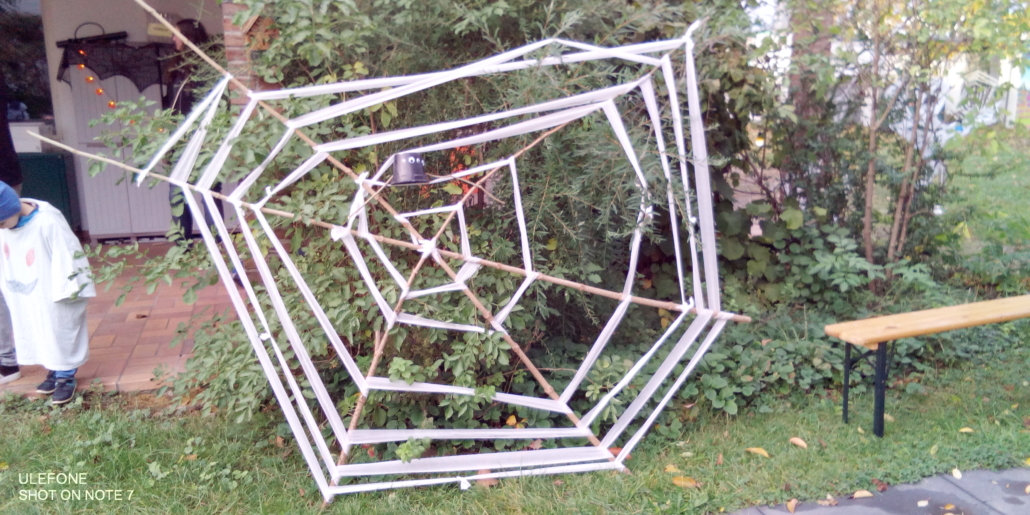 Das Foto zeigt ein großes Spinnennetz aus Ästen und Mullbinden, das als Dekoration im Garten aufgestellt wurde. (Foto: Stadtjugendring Regensburg)